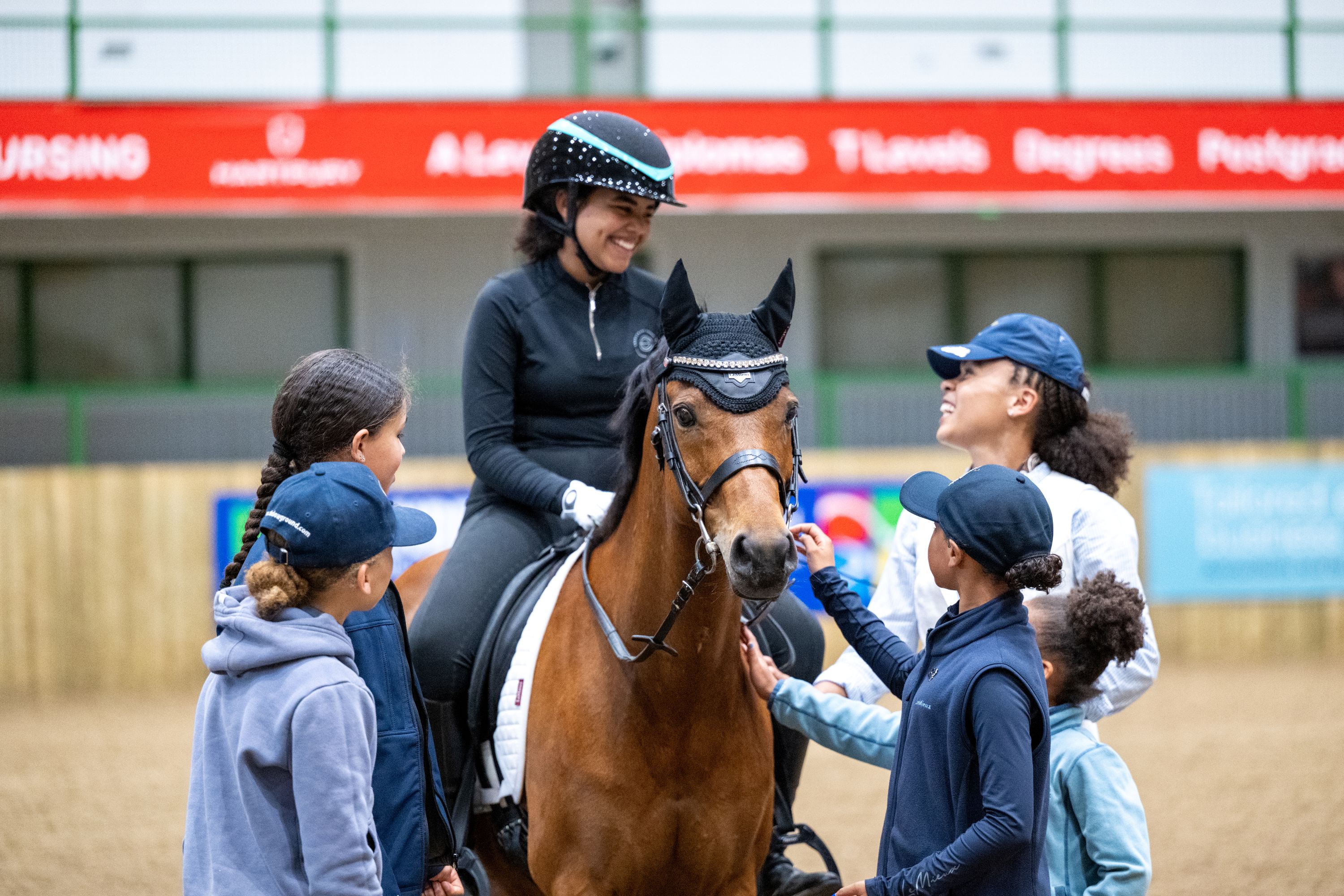 Friends gathered round rider and bay pony, all smiling.